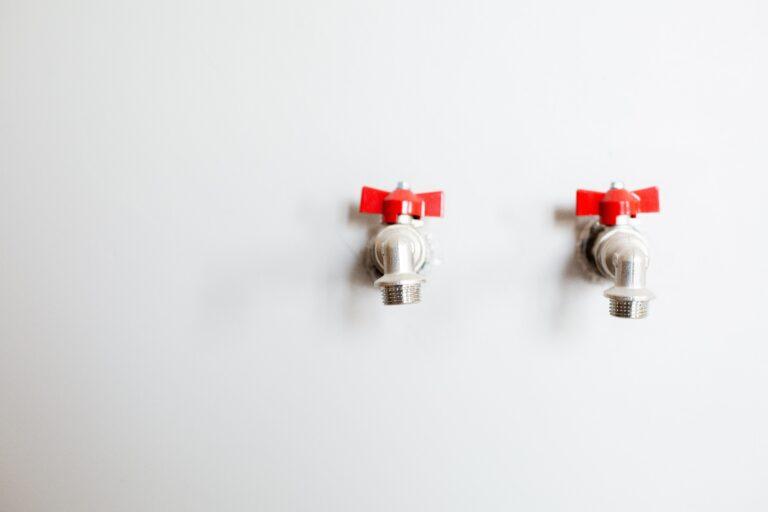 Three red water valves on white wall