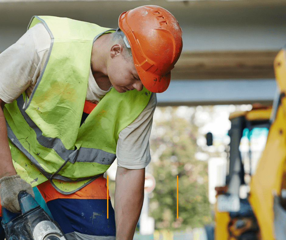 Construction worker using power tool outdoors.