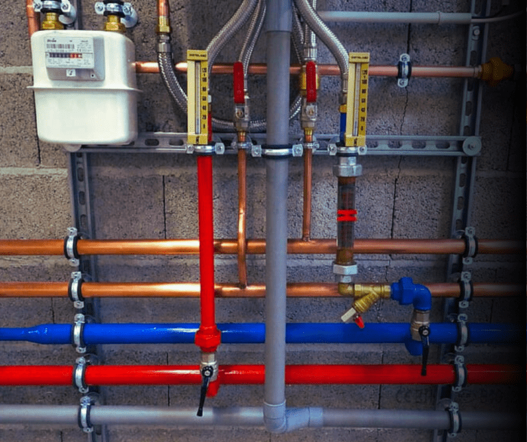 Industrial piping and gas meter on wall.