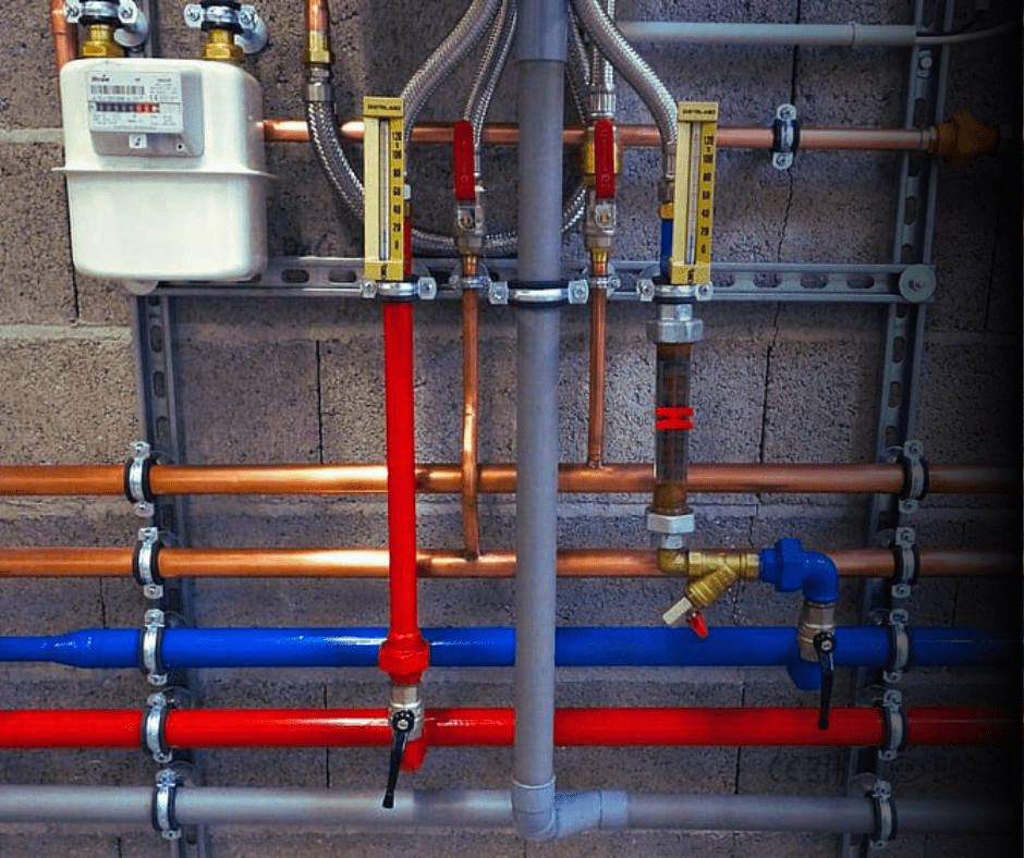 Industrial piping and gas meter on wall.