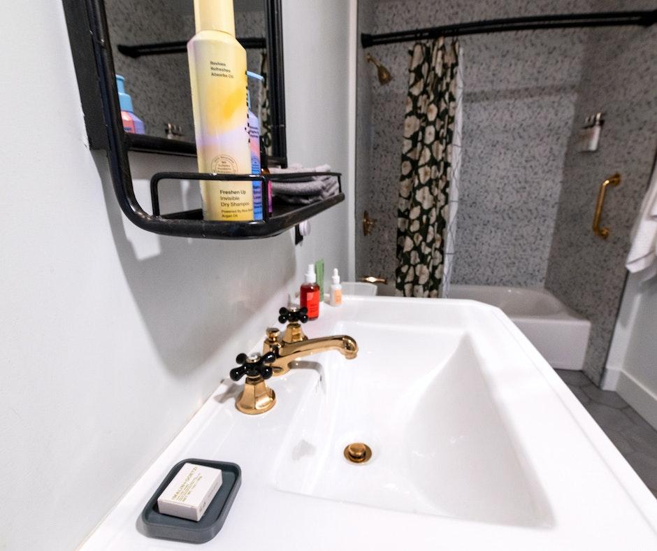 Modern bathroom with sink and gold fixtures.