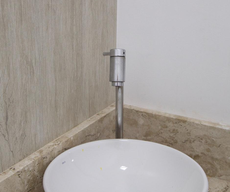 Modern bathroom faucet over white basin.