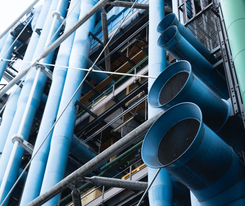 Industrial building exterior with large blue pipes.