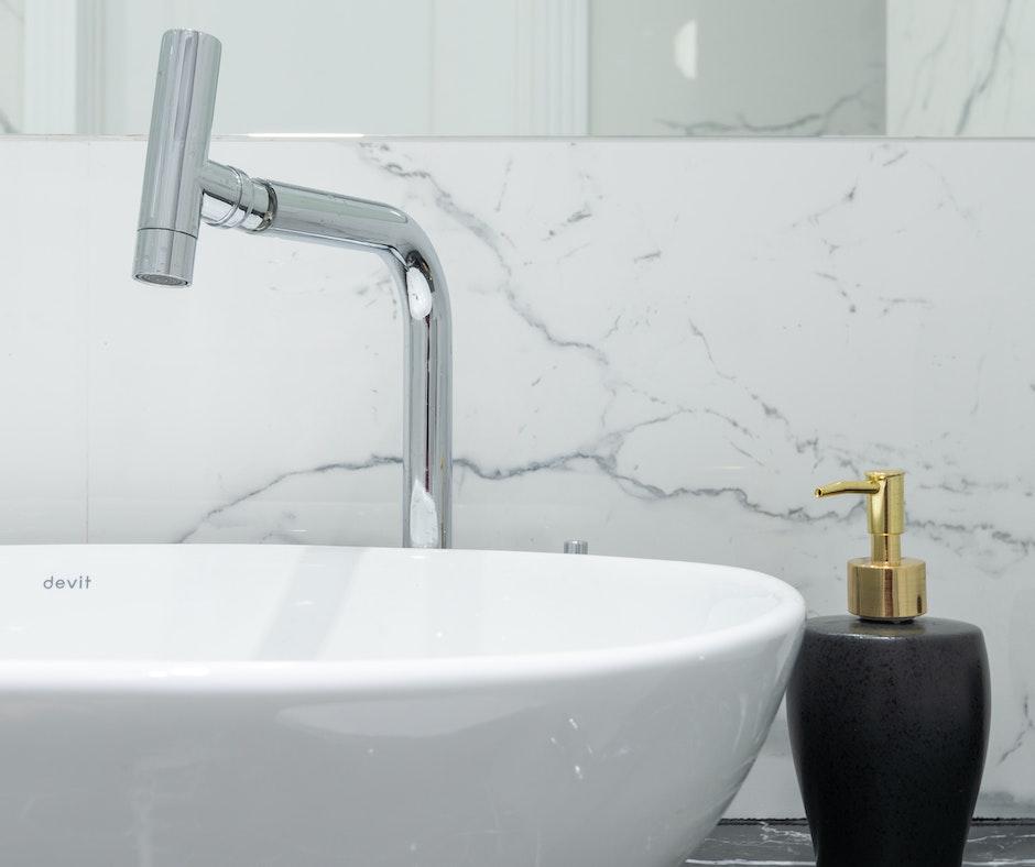 Modern bathroom sink with chrome faucet and marble backdrop.