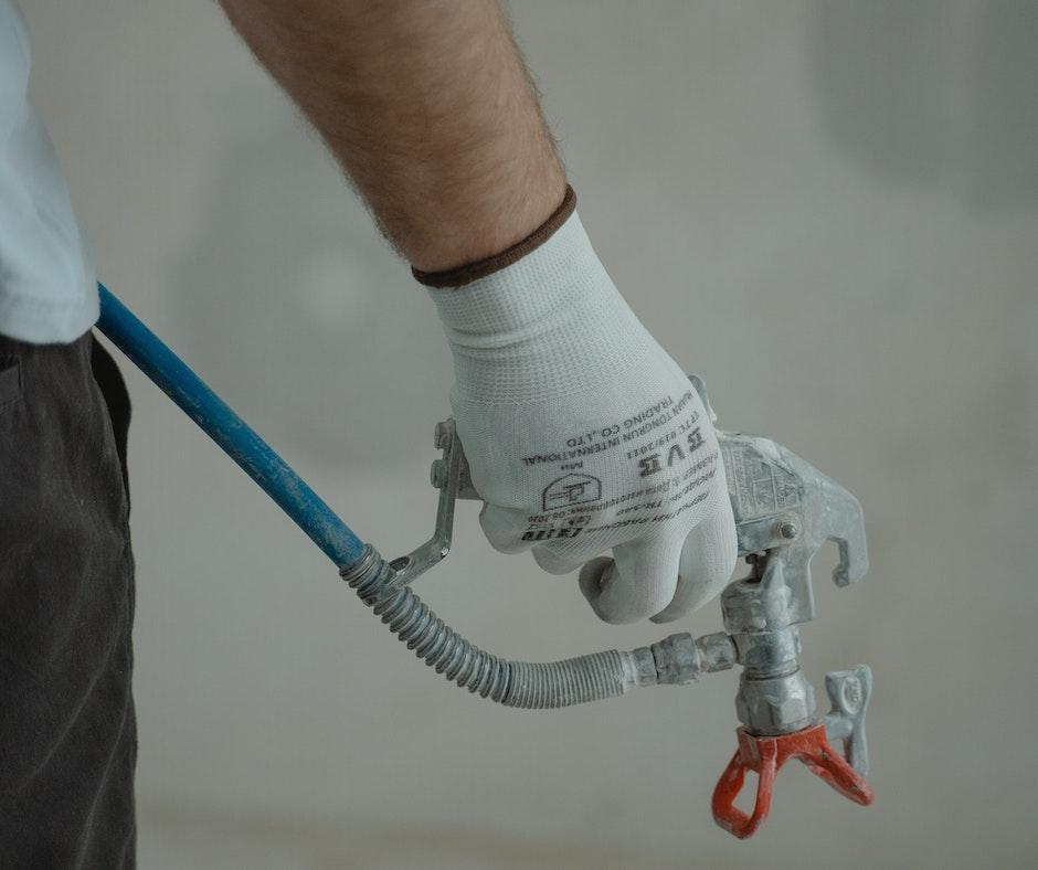 Person holding a paint spray gun with hose.