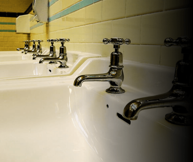 Row of white ceramic bathroom sinks with faucets.