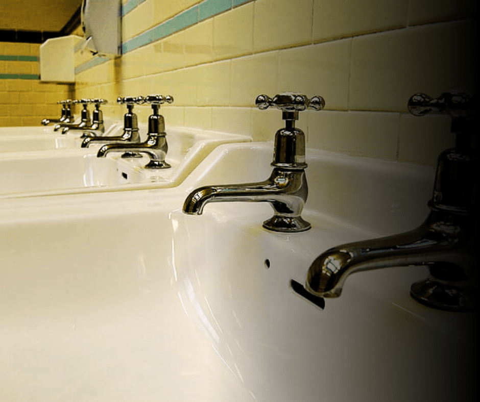 Row of white ceramic bathroom sinks with faucets.