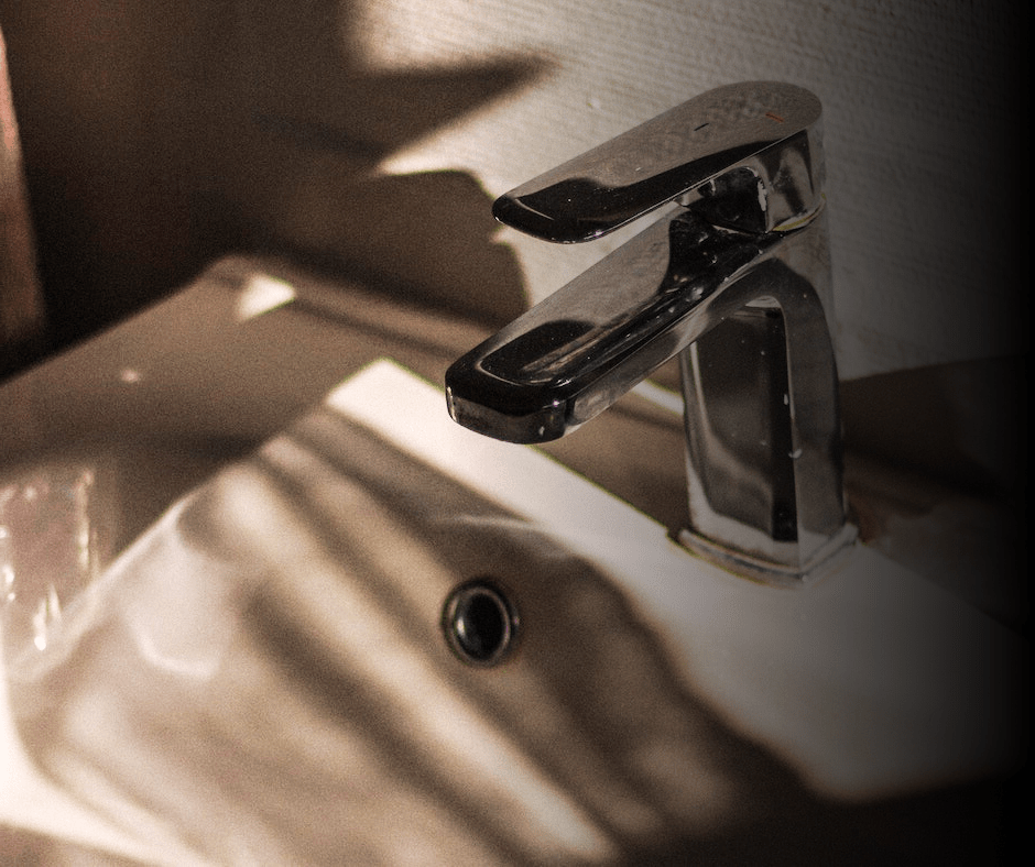 Chrome faucet over sink with shadows.