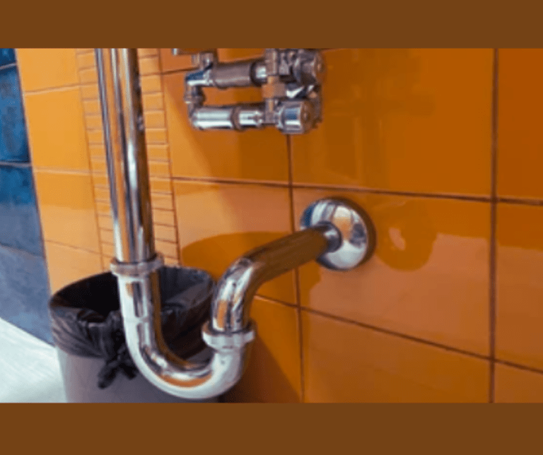 Chrome pipes against orange tiled wall.