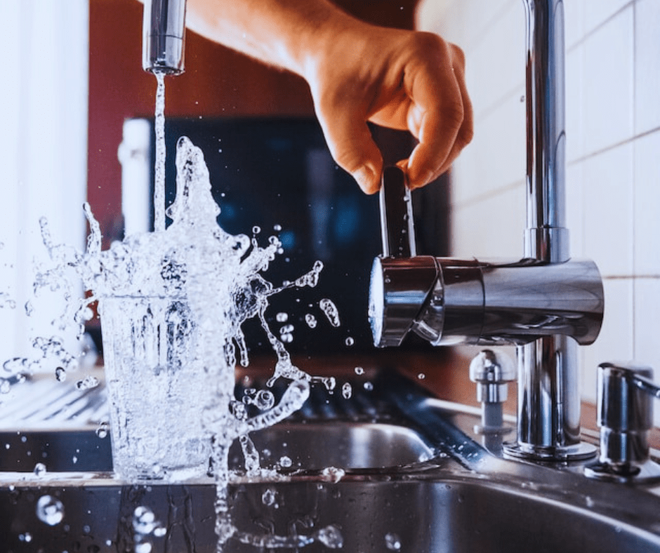 Water splashing from glass under running faucet.