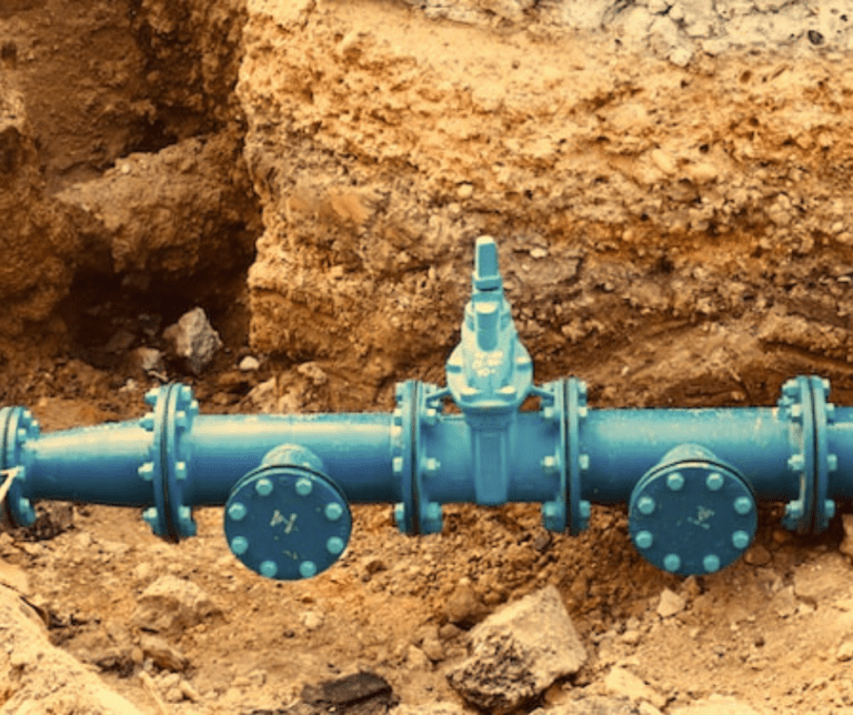 Blue underground water pipeline installation at construction site.