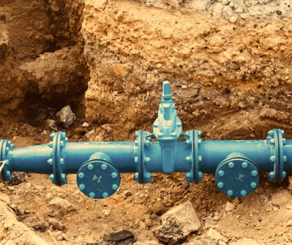 Blue underground water pipeline installation at construction site.