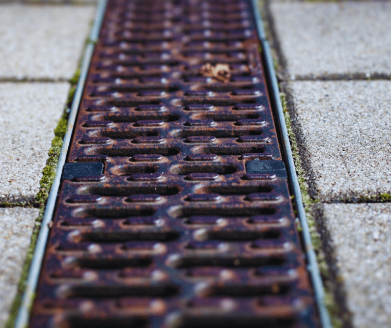 Rusty metal drain cover on pavement
