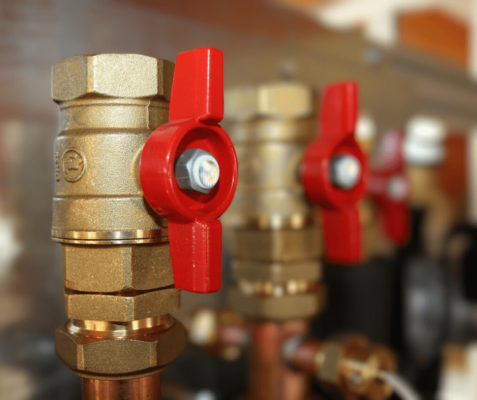 Red valves on brass plumbing pipes.