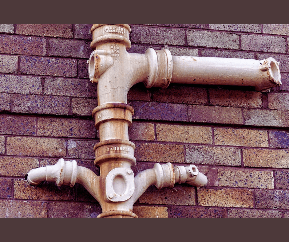 Rusty pipe on brick wall.