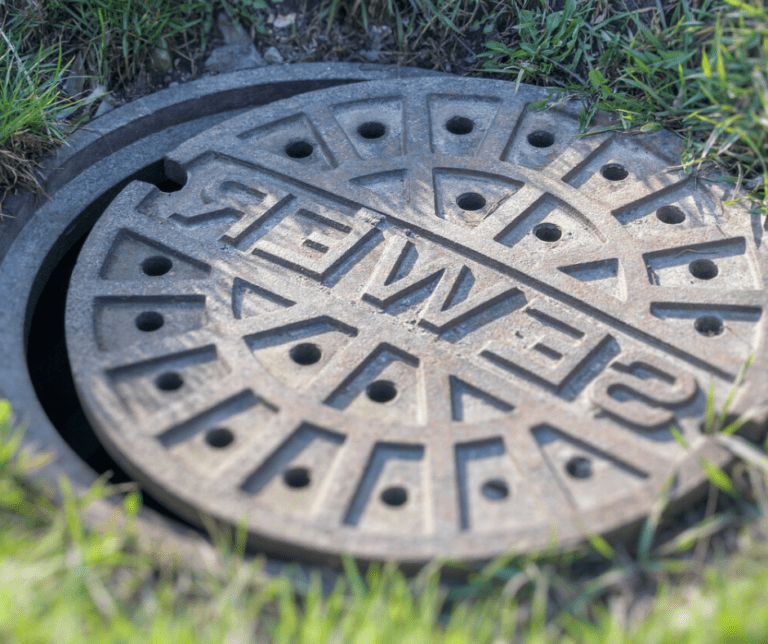 Iron manhole cover surrounded by grass.